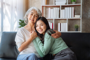 Happy granddaughter taking care of her grandmother sitting on the sofa.