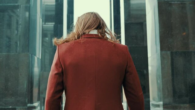Portrait of attractive bearded hipster man in red fashion coat. Thoughtful and resolute look in big town. Modern businessman model with long hair. Slow motion 