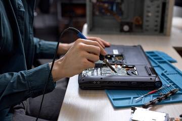 Cropped unrecognizable man disassembles broken laptop. Computer service and repair concept. Laptop disassembling in repair shop, workshop. Electronic development by professional technician