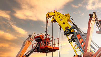 Articulated boom lift. Aerial platform lift and construction crane with sunset sky. Mobile construction crane for rent and sale. Maintenance and repair hydraulic boom lift service. Crane dealership. - obrazy, fototapety, plakaty