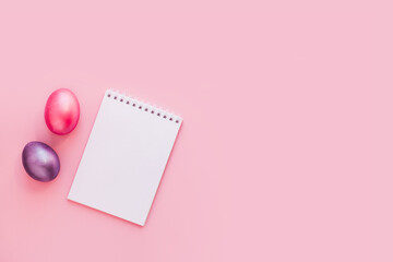 Flat lay with notebook mock up and colorful painted eggs on pink pastel background. Spring note trendy minimal holiday concept, place for text, logo, wishes. Empty space, list, mockup. Top view