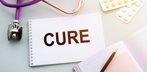 CURE text on a notepad with stethoscope, medical concept