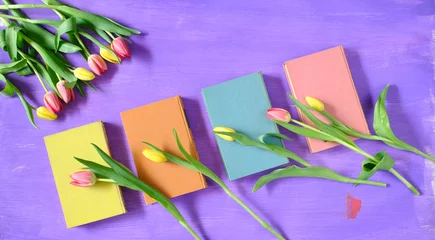 Fototapeten beautiful spring flowers, row of pink tulips flowers with books on purple background, concept, flat lay, negative space,free copy space © Kirsten Hinte
