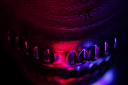 Vaso de cristal transparente para beber l&iacute;quidos tallado con una textura a rayas con l&iacute;nea curva en el centro, con luz azul y roja, forma un dise&ntilde;o abstracto original para los fondos