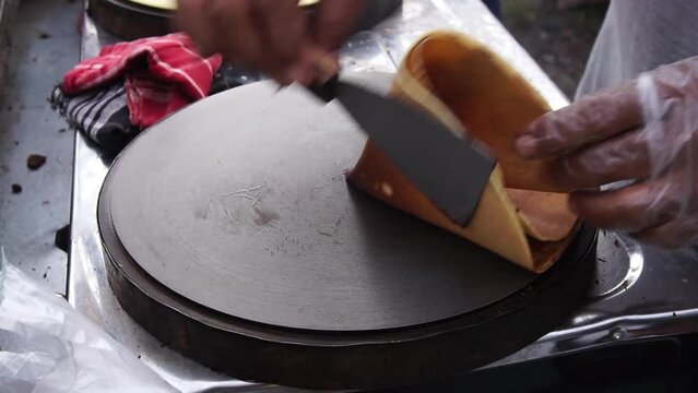The process of making crepes is filled with spread of chocolate and cheese. Thin pancakes, blini. Sweet dessert. close-up view