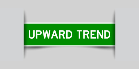 Inserted green color label sticker with word upward trend on gray background