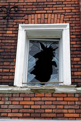 Broken window with white frame in a brick wall