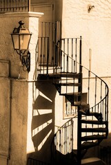 Vertical shot of a steel spiral staircase of an old building on a sunny day