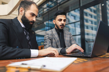 Business people outdoor meeting. A group of business people meet outdoors. Two men are using a laptop. Working break. Team and business support