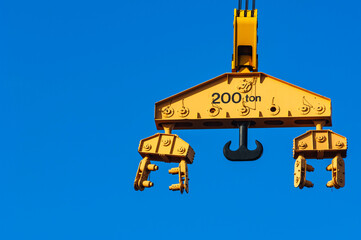 A giant blue crane stands under a clear sky, lifting a heavy 200 ton load and reading its chart.