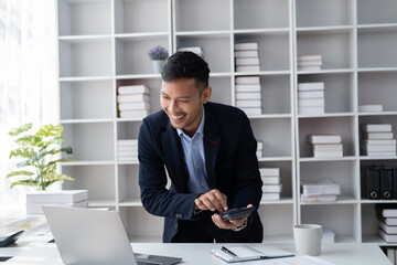 Confident handsome businessman bending over to his desk while using the calculator for the project.