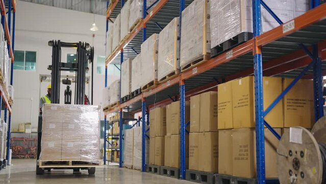 Retail Warehouse full of Shelves with Goods: Electric Forklift Truck Operator Lifts Pallet with Cardboard Boxes On a Shelf. People Working, Scanning Products, Using Trucks in Distribution Center