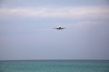 Fototapeta na wymiar A large plane lands over the sea and the beach. Beach near the airport. A beautiful plane.