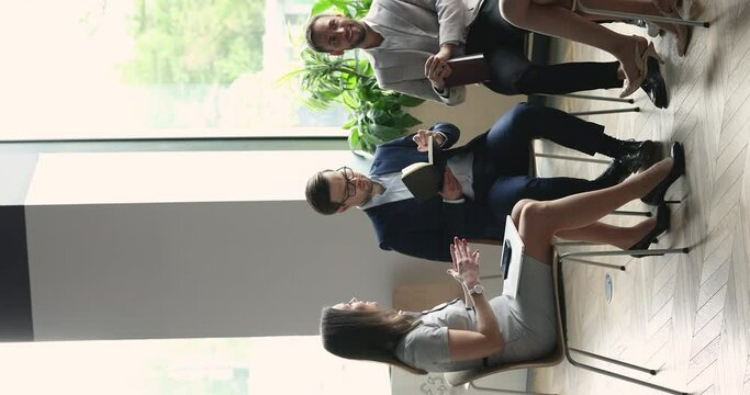 Confident businesswoman speaking to team on corporate briefing, giving instructions. Group of employees working together, sitting in circle in office, talking, brainstorming