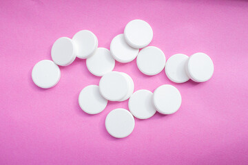 White soluble tablet pills isolated on a pink background. Top view, flat lay.