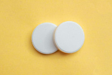White soluble tablet pills isolated on a yellow background. Top view, flat lay. - obrazy, fototapety, plakaty