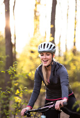 Pretty, young woman with her mountain bike going for a ride past the city limits, getting her dose of daily cardio