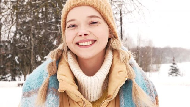 Young beautiful smiling hipster female in trendy warm clothes and scarf.Carefree woman posing in the street in park. Positive pure model having fun in snow. Enjoying winter moments