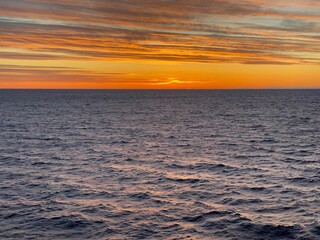 Obraz premium Die Sonne geht unter nach einem sonnigen Wintertag über dem Skagerrak. Der Himmel ist orange gefärbt. Auf dem Meer sorgt das spärlichere Licht für sanfte Schatten in der Nähe der schwedischen Küste.