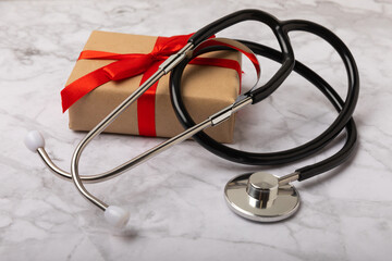 National Day of Doctors. Modern stethoscope, gift box and gingerbread in the form of medical supplies on a marble background. .Gingerbread in the form of a thermometer, a medical mask, a pill, a patch