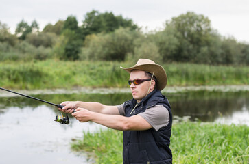 Fisherman in a hat on the river bank