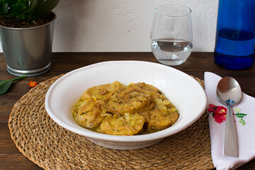 Plato de patatas guisadas sobre mantel individual redondo de mimbre. Cocina tradicional española. 