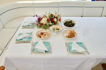 Overhead yacht-deck lunch: mixed meze plates, roast chicken, fresh flowers and aqua napkins...