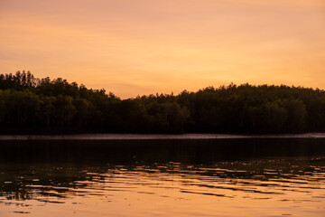 Obraz premium Sunrise view with colorful sky and the sea, with silhouette of the forest on the background
