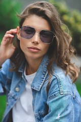 Hipster girl in clean white t-shirt and jeans posing against the background of buildings, minimalist urban clothing style