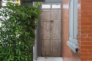 Wooden door by tree and wood window and brick wall