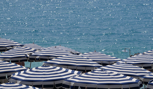 Parasols blancs et bleus et mer bleue sur une plage priv&eacute;e. C&ocirc;te d'azur, France