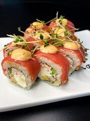 sushi and rolls on the white Japanese plate on black background