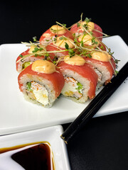 sushi and rolls on the white Japanese plate on black background
