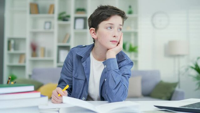 Bored schoolboy do task Tired exhausted sad upset fatigued little child boy kid pupil schoolboy schoolchild lying on table desk writing homework boring class lesson drawing in notebook at home