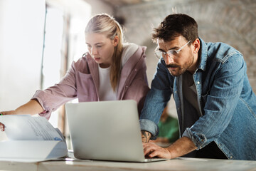 Two architects cooperating while working on a computer in the office