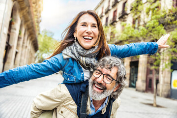 Happy senior couple having fun walking on city street - Two older tourists enjoying together...