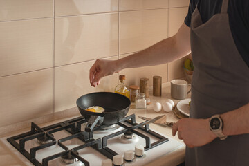 Young man preparing toast with avocado and egg for breakfast in the kitchen