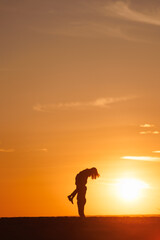 silhouettes of couple at sunset against bright sun sky. man and woman have fun in nature, walking and relaxing, relationships and falling in love. poster postcard romantic meetings against background 