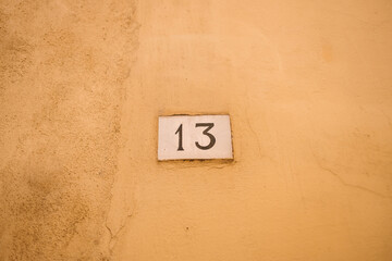 House number 13 on on a orange stone wall. Thirteen with copy space.