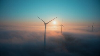 Wind farm at sunrise in heavy fog. Wind turbines generating green energy - concept of renewable electricity, sustainable energy, green power production - Powered by Adobe