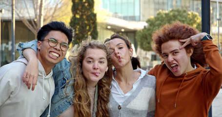 Group portrait of a group of smiling teenagers embracing each other looking at camera 