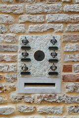 Detail of a stone intercom and mail slot decorated with metal heads of witches, Venice, Veneto, Italy