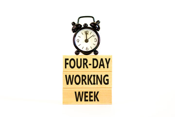 Four-day working week symbol. Concept words Four-day working week on wooden block on a beautiful white table white background. Black alarm clock. Business four-day working week concept. Copy space.