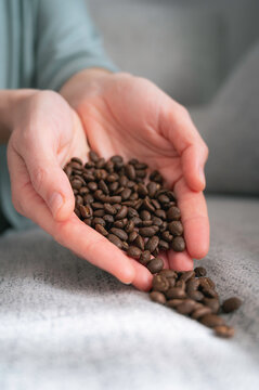Close-up image of young woman's hands, heart-shaped, holding and dropping coffee beans