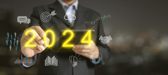 Unlock Success in 2024. A businessman points to the Glowing Text of 2024, surrounded by relevant Business Icons.