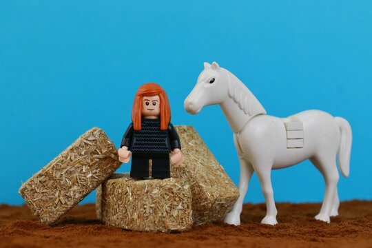 Red-haired farmer female Lego figurine standing on hay bales and a horse