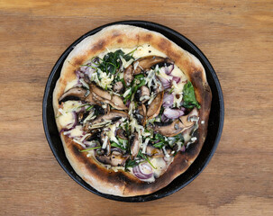 Mushroom pizza. Top view of a pizza with mushrooms, spinach, mozzarella and parmesan cheese with a wooden background.