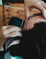 Closeup shot of a male barber working with a blade to style and line up hair