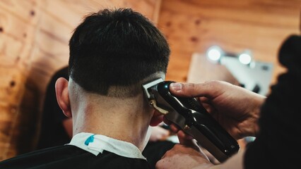 Closeup shot of a male barber working with an electric razor to style hair