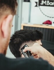 Closeup shot of a male barber working with an electric razor to style hair